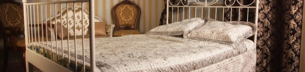 Elegant bedroom with vintage white metal bed, textured bedding, and ornate brown patterned curtains