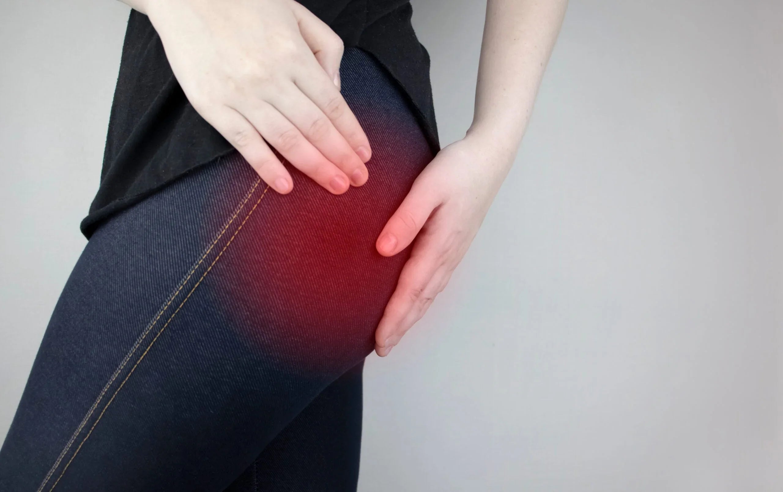 Person holding hip with red highlight indicating piriformis syndrome pain on thigh