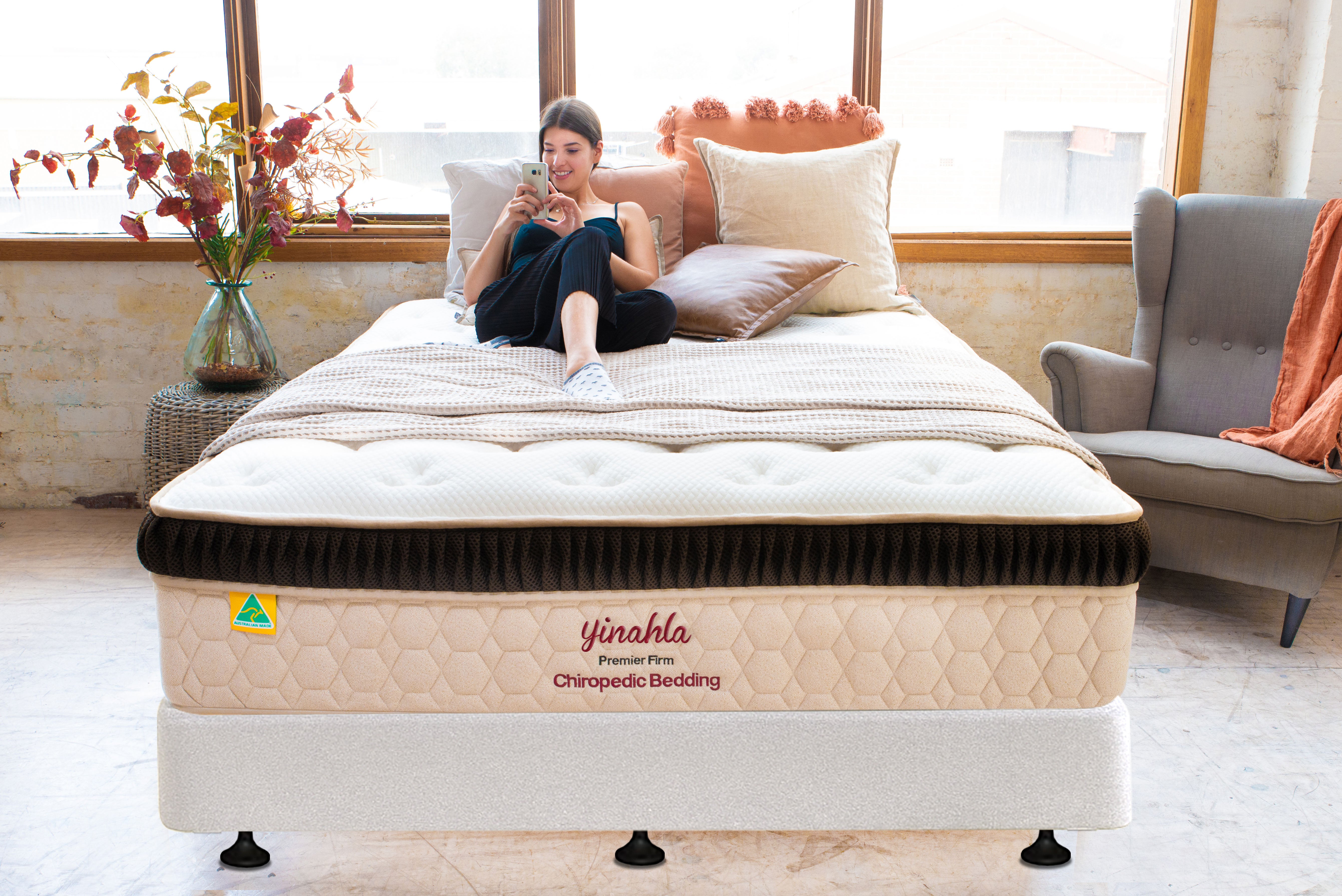 Woman relaxing on a Premier Firm Yinahla orthopedic mattress in a bright, cozy bedroom setting