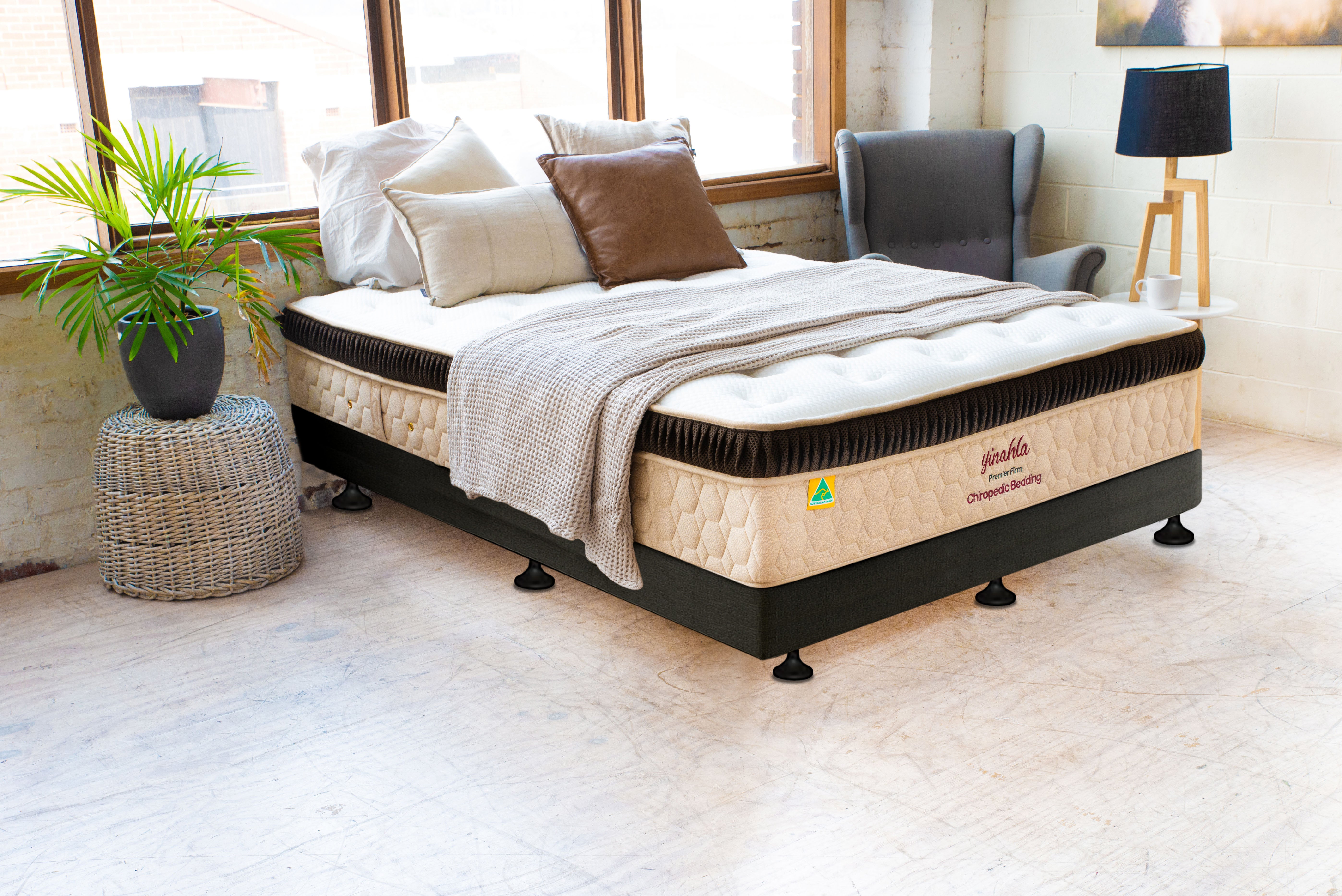 Modern bedroom with Premier Firm chiropractic mattress, bedding, armchair, and plant near window