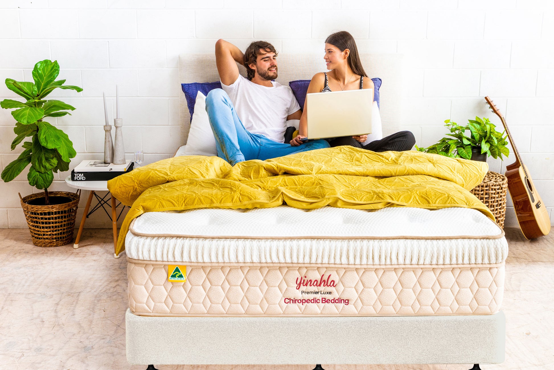 Couple relaxing on Yinahla Premier Luxe orthopedic mattress with yellow bedding in modern bedroom