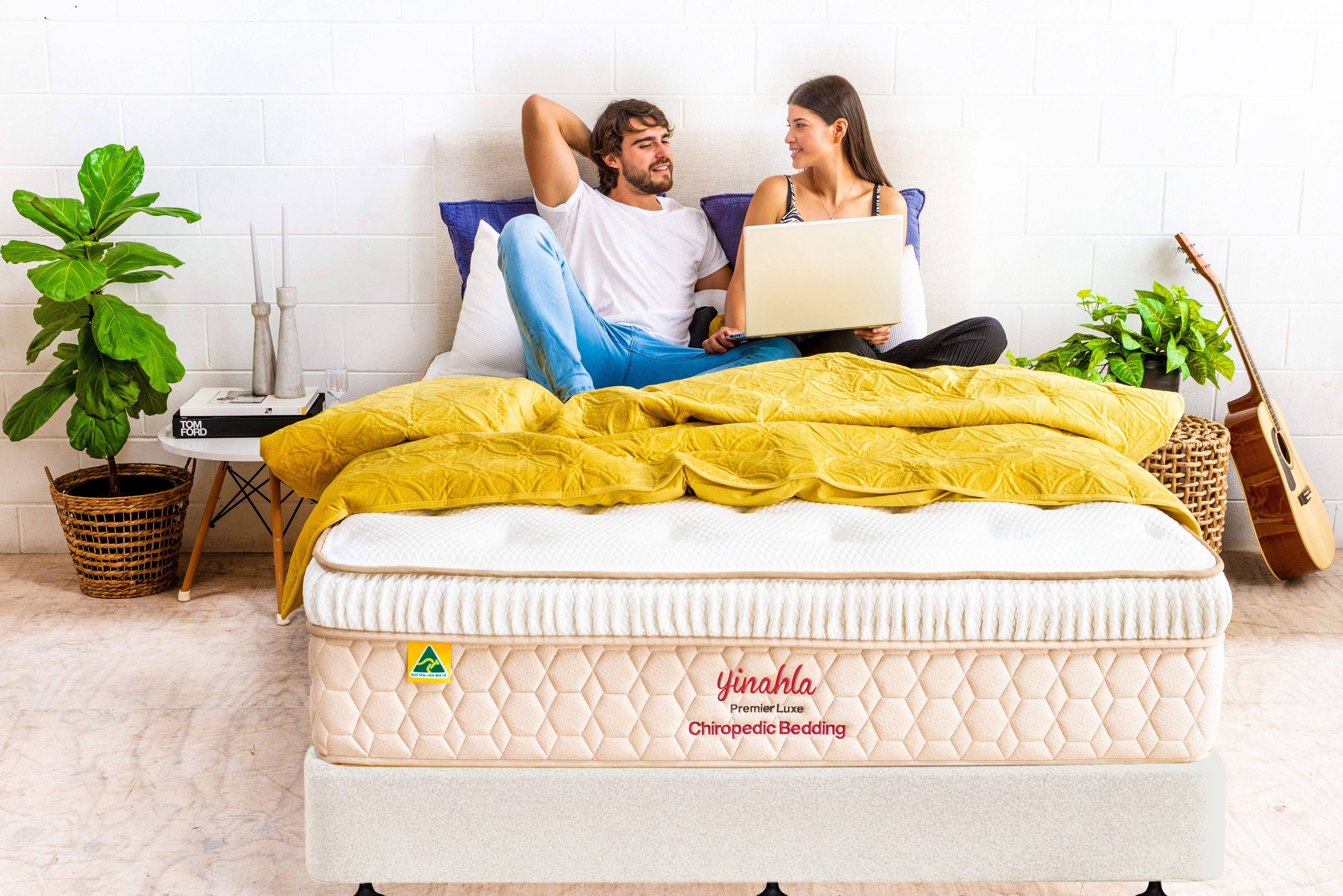 Couple relaxing on Yinahla Premier Luxe orthopedic mattress with yellow bedding in modern bedroom