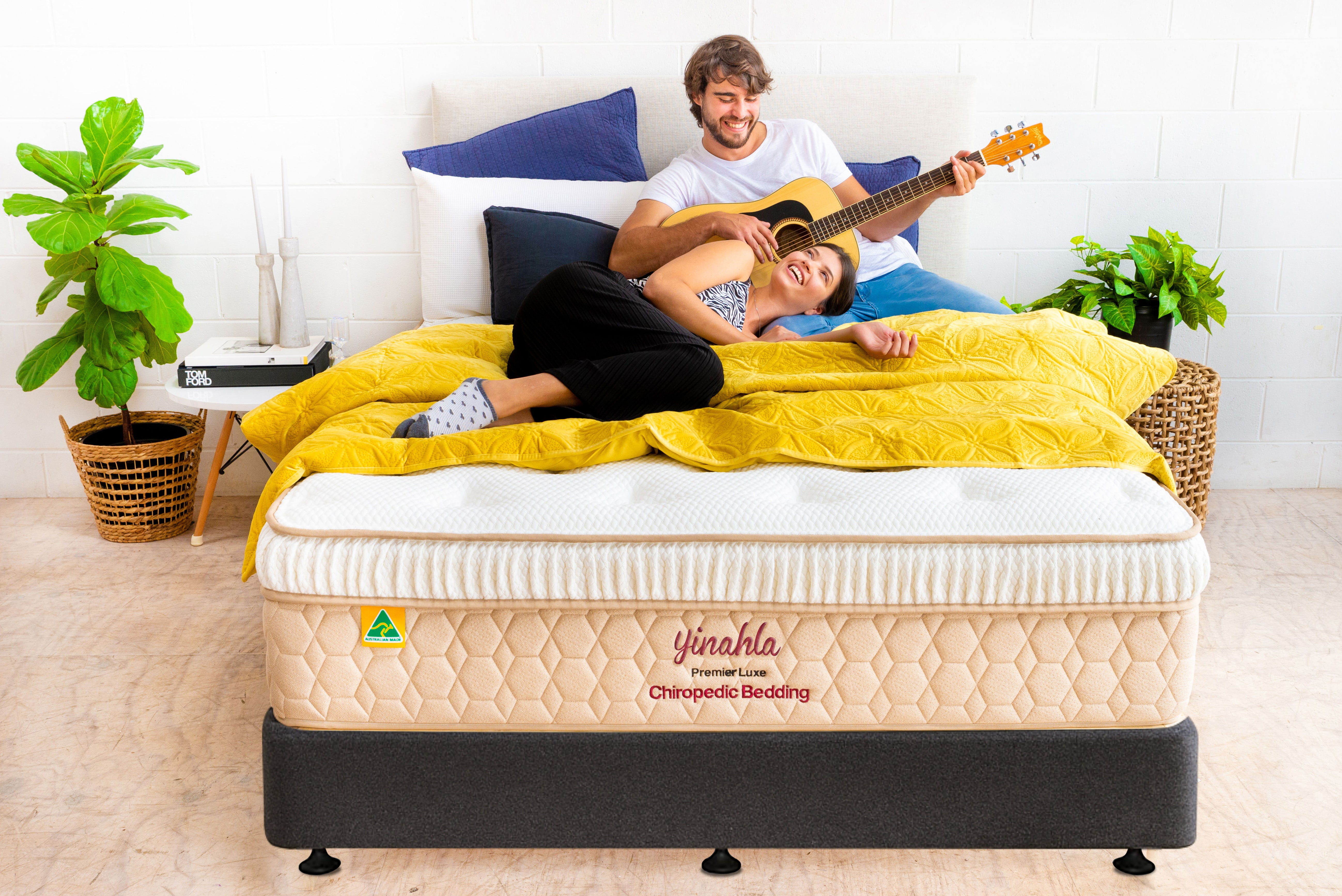 Couple enjoying music on a yellow quilt-covered bed with Yinahla Premier Luxe Chiropedic mattress