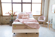 Stylish bedroom with yinahla Visco Flex orthopedic mattress, pink bedding, soft chair, and large window