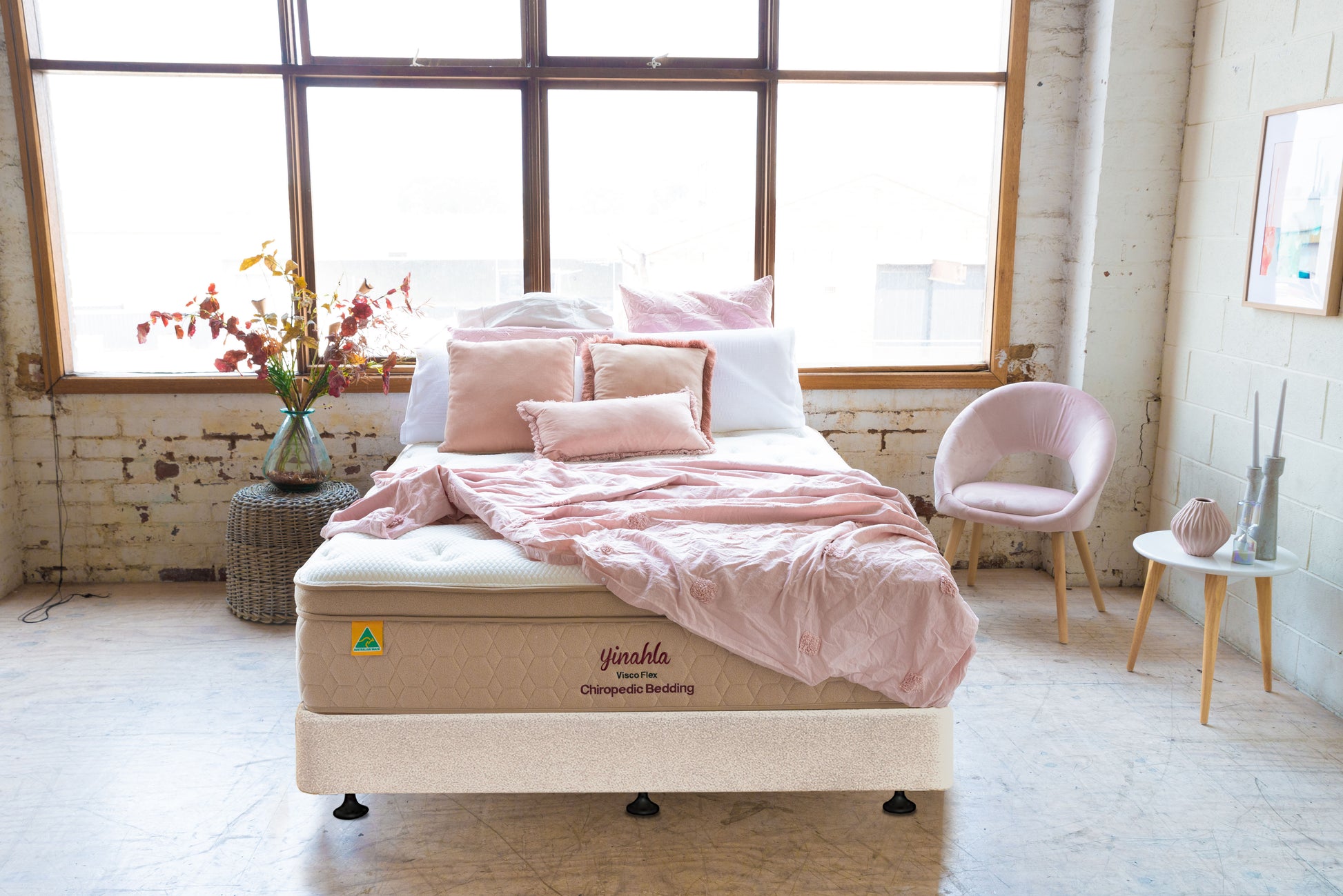 Stylish bedroom with yinahla Visco Flex orthopedic mattress, pink bedding, soft chair, and large window