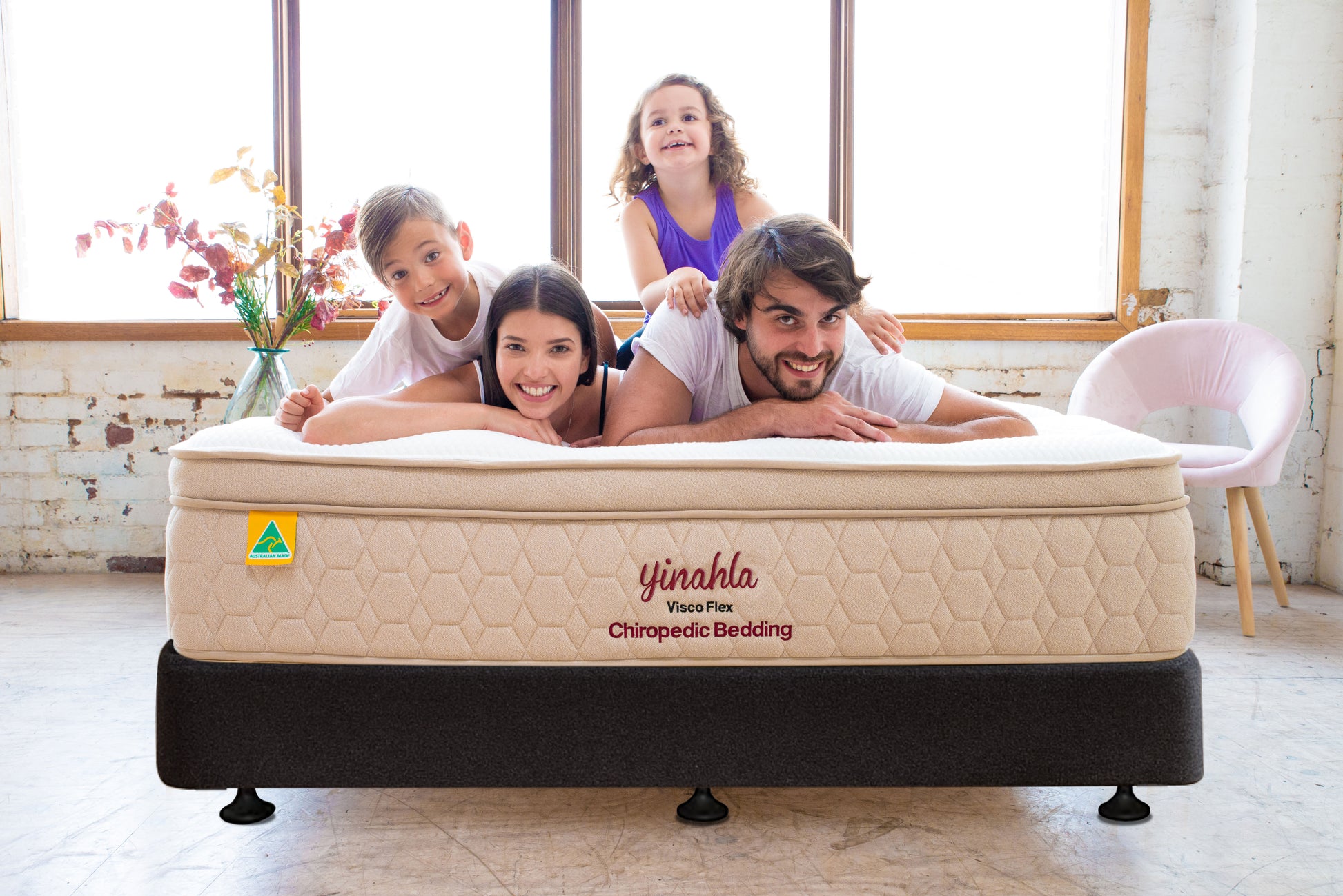 Happy family of four on Yinahla Visco Flex Chiropedic mattress in bright room with large windows