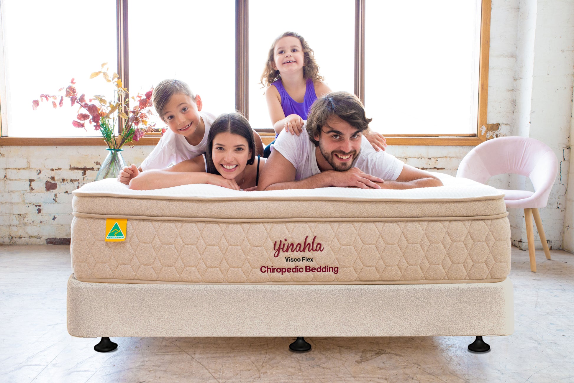 Happy family of four lying on Yinahla Visco Flex Chiropedic Bedding mattress in bright cozy room